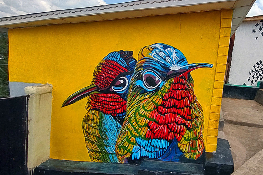 A mural of two colorful birds painted on a yellow wall